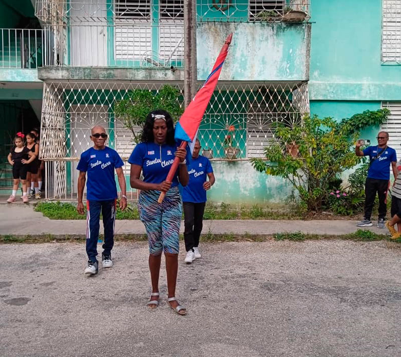 María Elena León y otras glorias deportivas portan la bandera en la inauguración de los Juegos Deportivos Recreativos Comunitarios.
