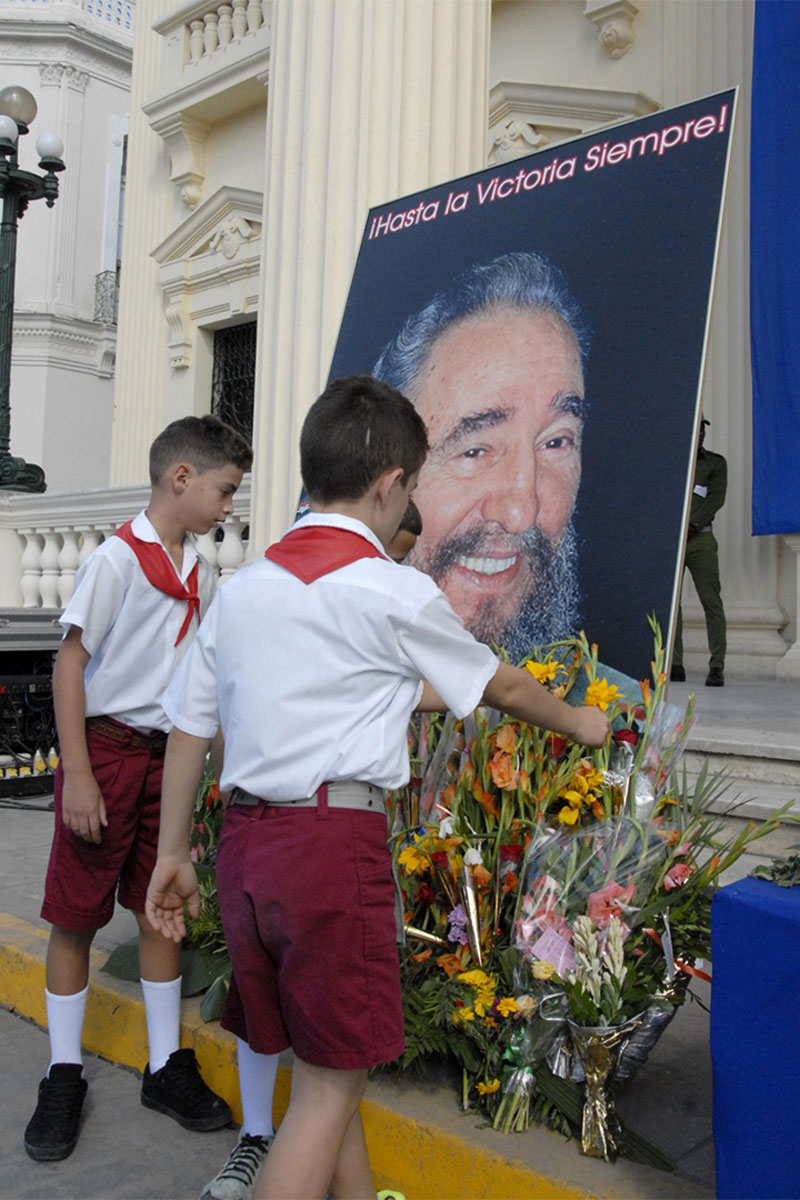 Pioneros colocan flores ante foto de Fidel.
