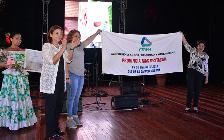 La titular del Citma, Dra. Elba Rosa Pérez Montoya, entrega la Bandera que le acredita a Villa Clara la sede nacional por el Día de la Ciencia Cubana.