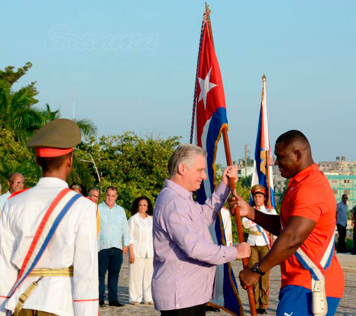 Presidente cubano, Miguel Díaz-Canel, entrega bandera cubana al campeón olímpico de lucha Mijaín López.