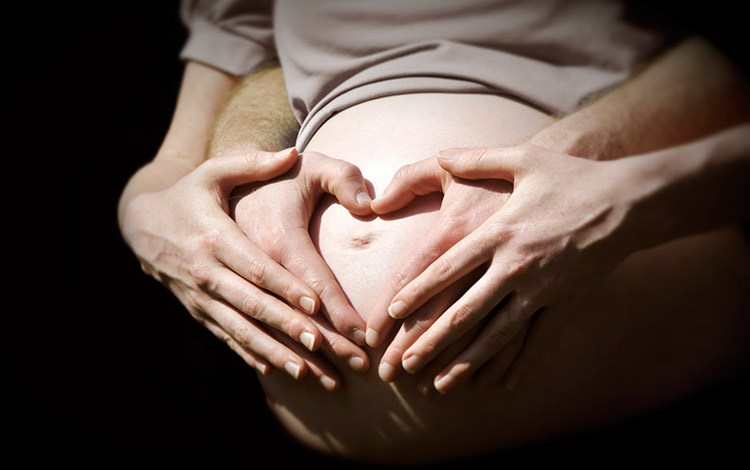 Hombre acarica barriga de esposa embarazada.