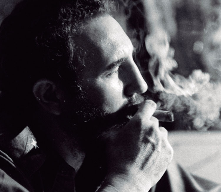 Fidel Castro Ruz de perfil fumando tabaco.