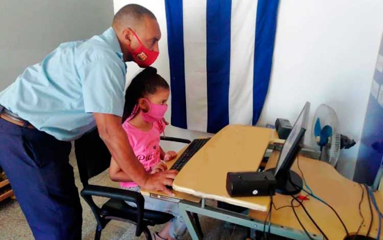 Instructor de Joven Club de Computación enseña a niña.