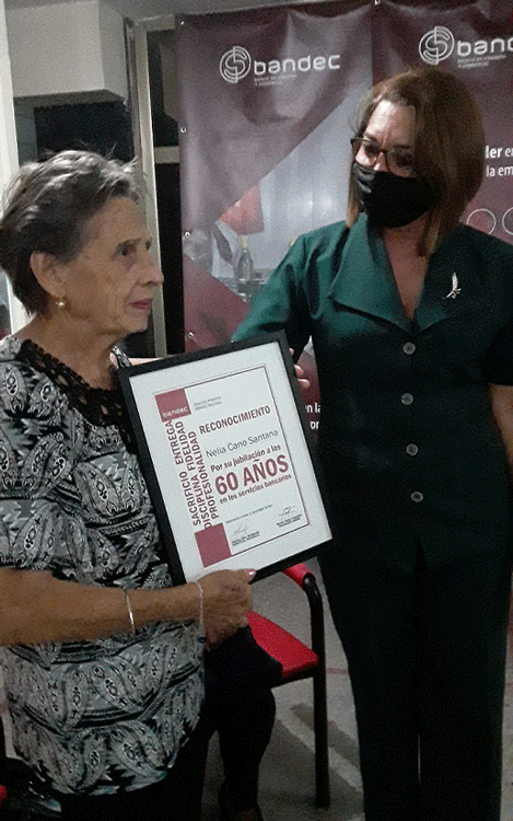 Por su entrega, compromiso, y años de labor, Nelia Cano Santana recibió el reconocimiento de sus compañeros de trabajo, de manos de Emelina Báez Abrahantes, directora de Bandec en Villa Clara. Por su entrega, compromiso, y años de labor, Nelia Cano Santana recibió el reconocimiento de sus compañeros de trabajo, de manos de Emelina Báez Abrahantes, directora de Bandec en Villa Clara.