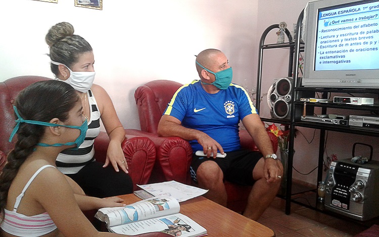 Padres e hija viendo las teleclases.
