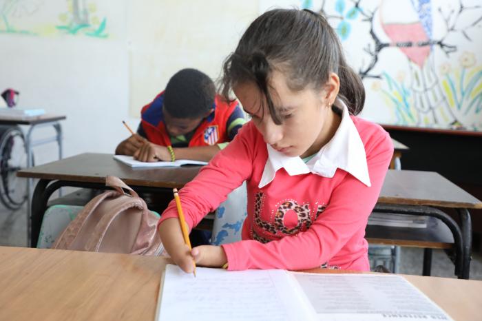 NIña con discapacidad escribe en la escuela Solidaridad con Panamá.