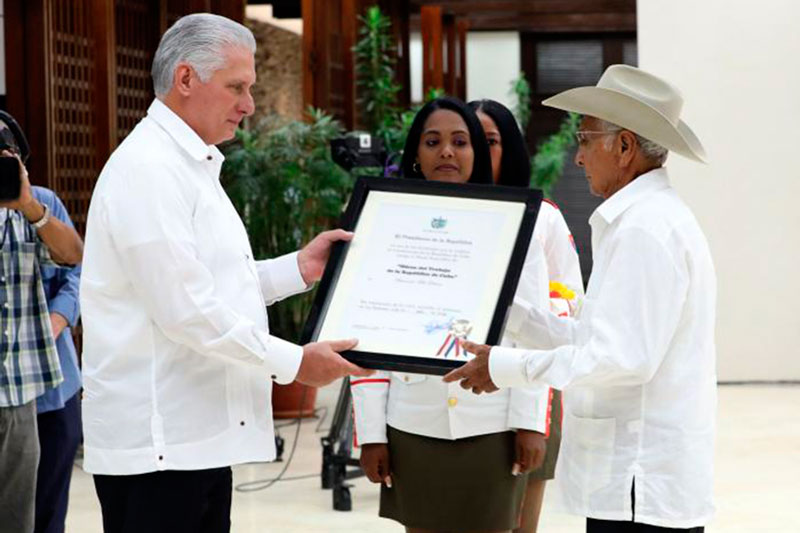 Presidente cubano condecora a campesino destacado.