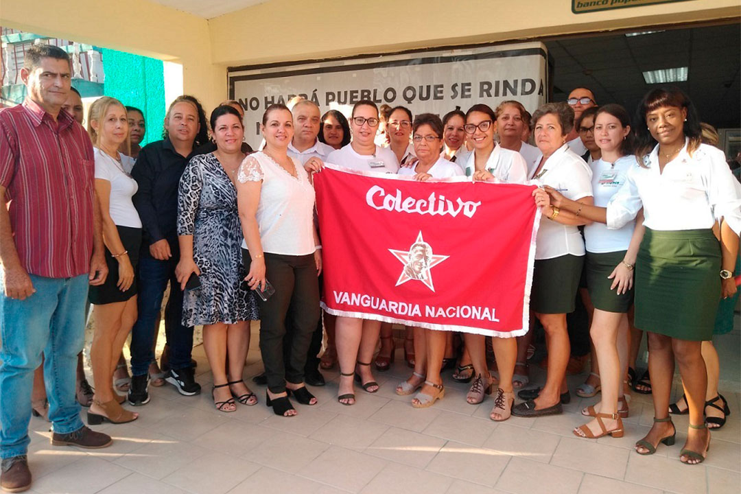 Colectivo de la sucursal 4282 del Banco Popular de Ahorro (BPA) de Villa Clara con la bandera de Vanguardia Nacional.