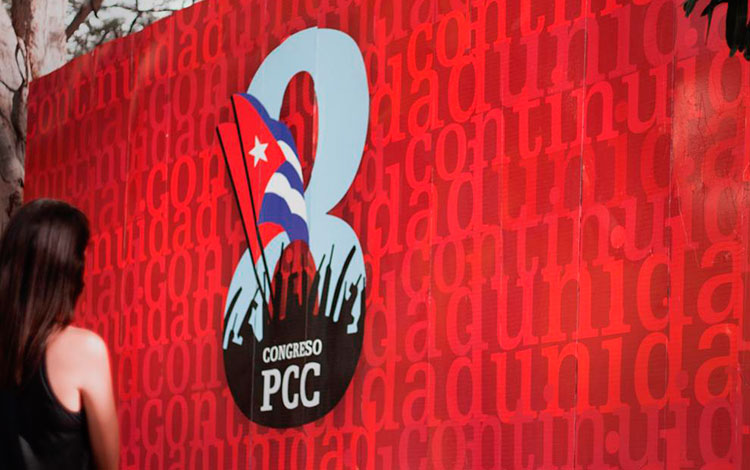 Joven ante una valla del 8.o Congreso del Partido Comunista de Cuba.