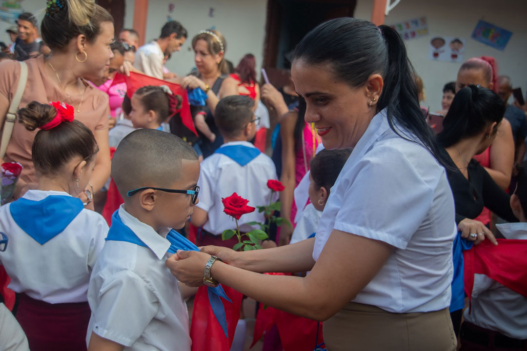 Madre cambia pañoleta azul a su hijo.