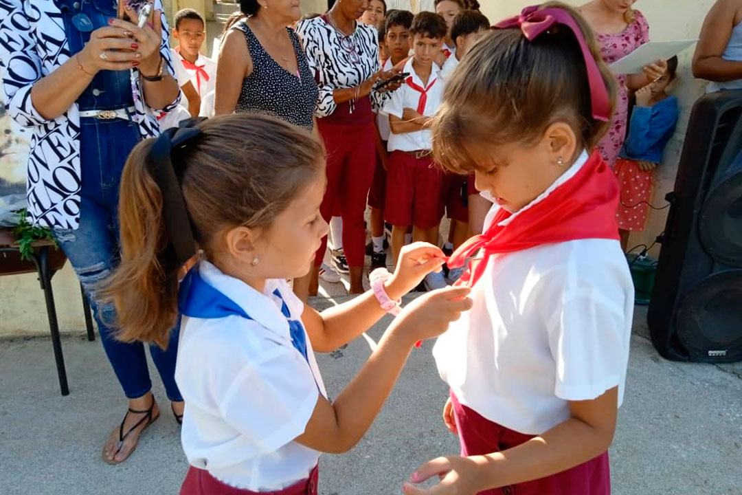 La pionera Déborah recibe la pañoleta de manos de su hermana.
