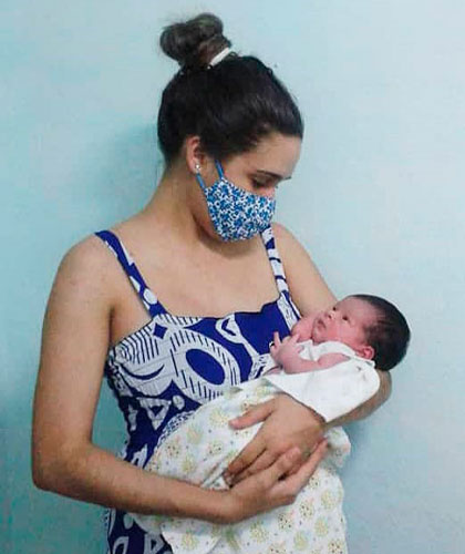 Madre protegida con nasobuco cargando su pequeño hijo. Madre protegida con nasobuco cargando su pequeño hijo.