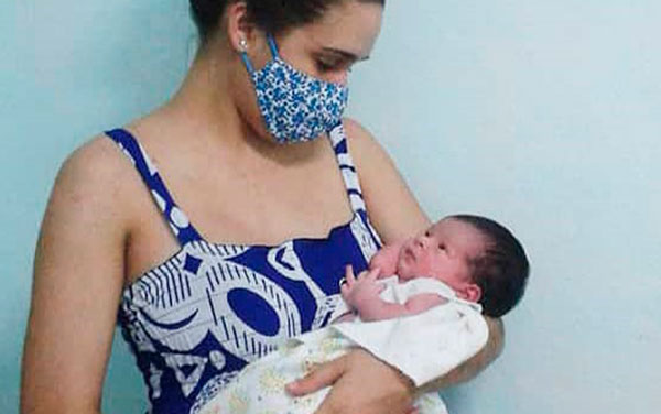 Madre protegida con nasobuco cargando a su hijo pequeño.